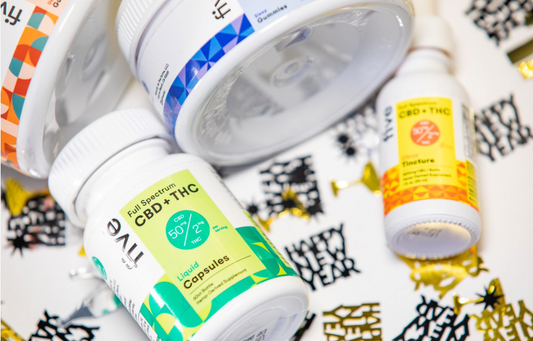 Bottles labeled Full Spectrum CBD + THC Liquid Capsules 50 mg CBD 2 mg THC and Tincture with CBD + THC 10% 1 fl oz (30 ml) on a surface with Happy New Year confetti.