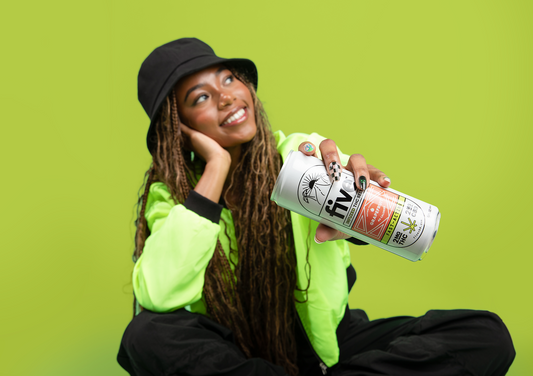 Angled close-up of Five THC seltzer can showing label and logo held by smiling woman in neon green hoodie on lime background